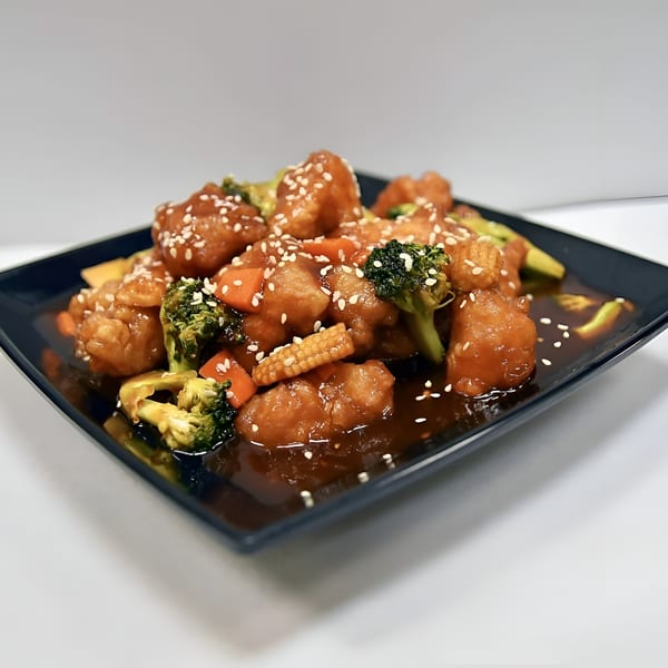 Thai sweet and sour chicken with broccoli, carrots, and baby corn, garnished with sesame seeds.
